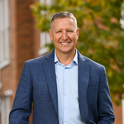 Headshot of James A. Throha from Juniata College, wearing a blue blazer and light blue shirt 